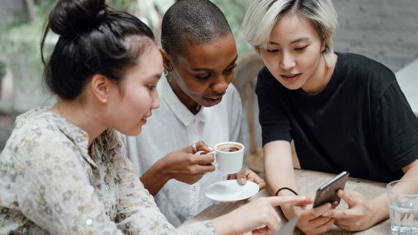 Amigas tomando café enquanto veem o celular